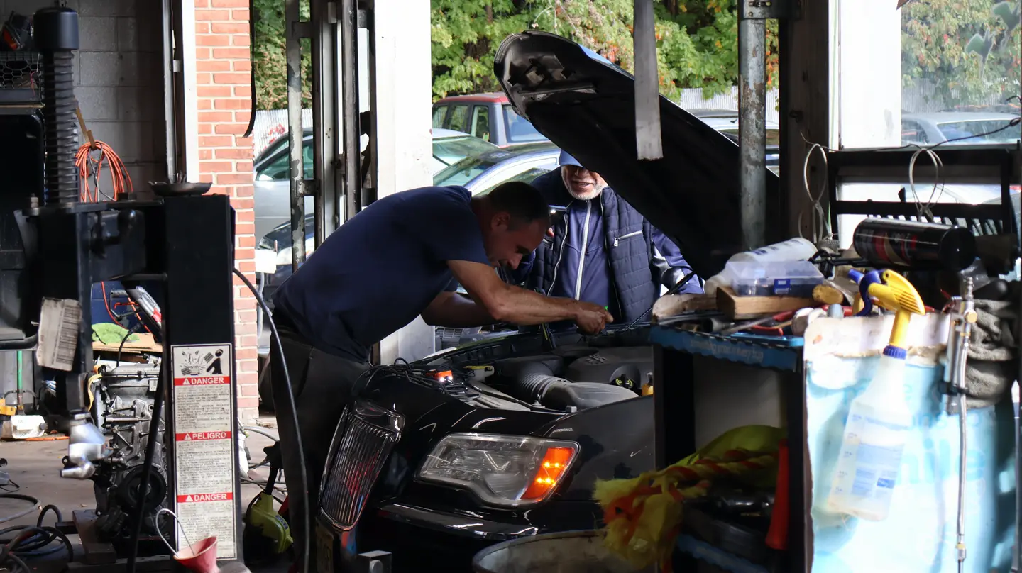 Mechanic working under an open hood at 4 Wheels Auto Repair